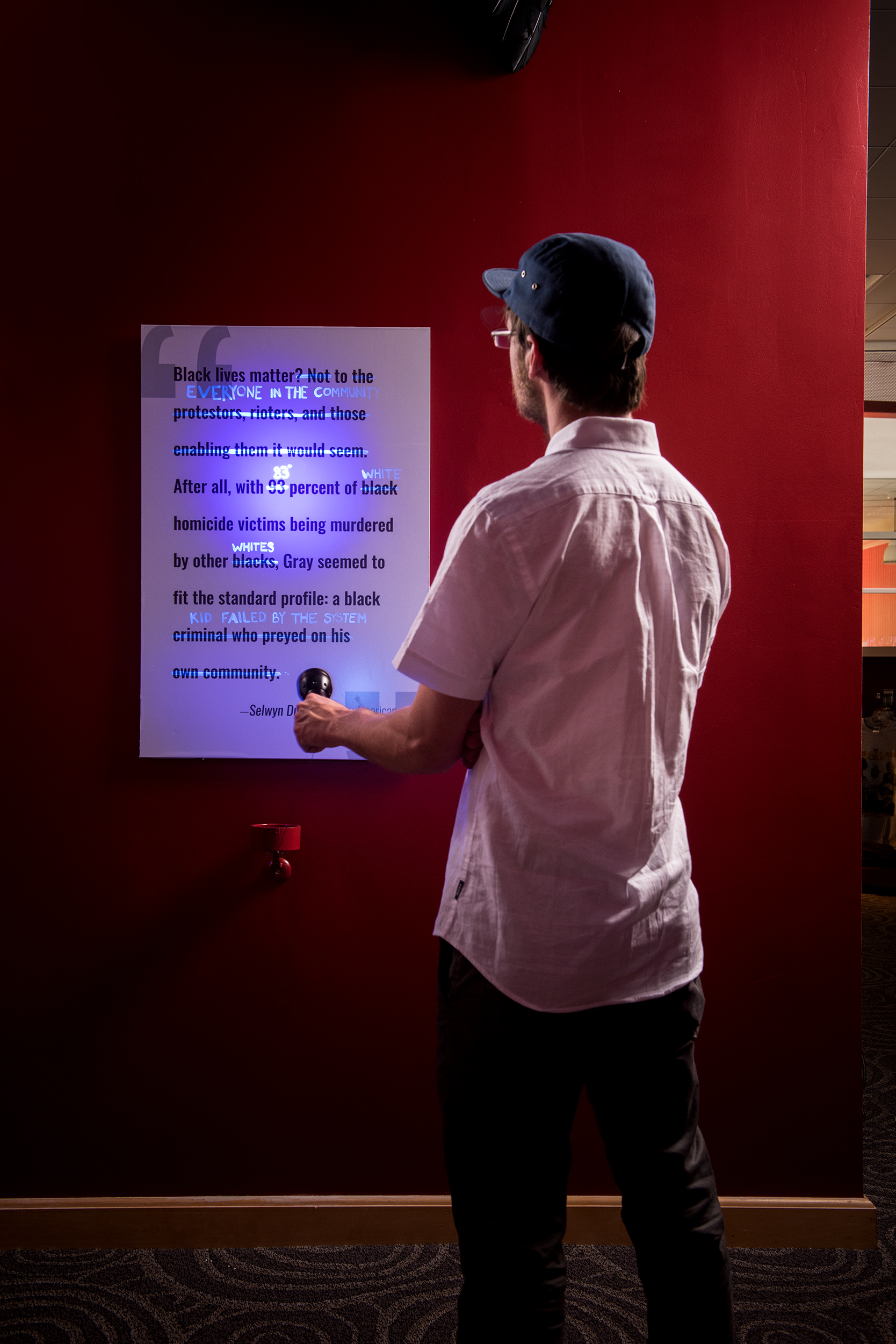 A man shines a blacklight on a poster. New words are revealed.