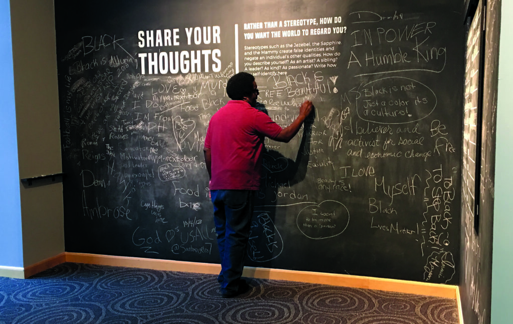 An attendee writes their thoughts on the chalk wall.