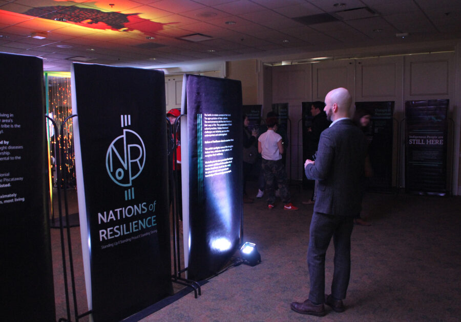 A visitor to the exhibit looking at the Nations of Resilience logo